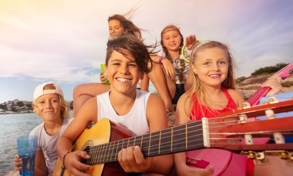 Young friends with guitar having fun outdoors